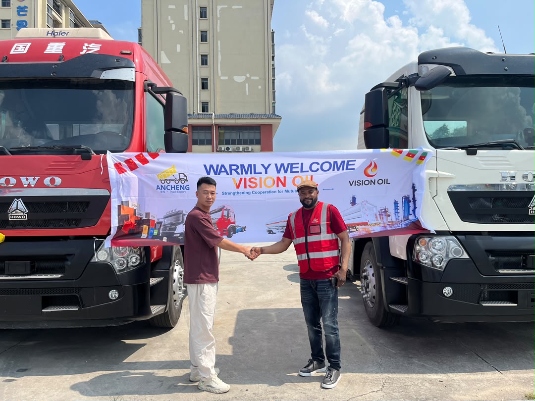 Handshake between Vision Oil and a Chinese partner in front of trucks with a Warmly Welcome Vision Oil banner