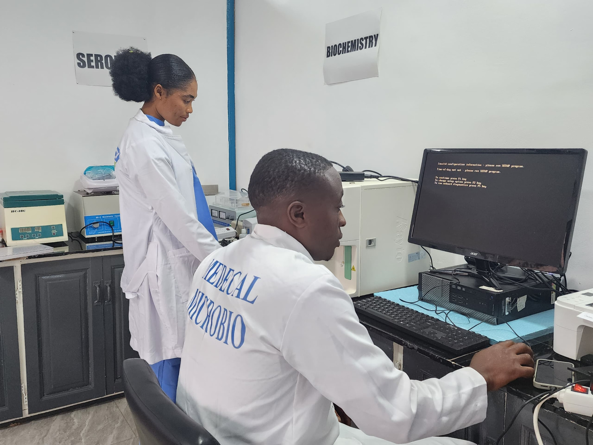 Laboratory staff recording patient results at a computer workstation